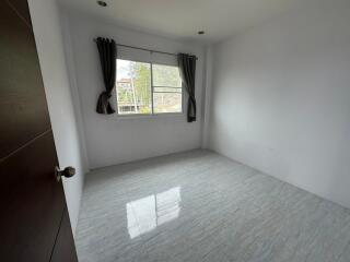 Small, unfurnished bedroom with a window, tiled floor, and white walls