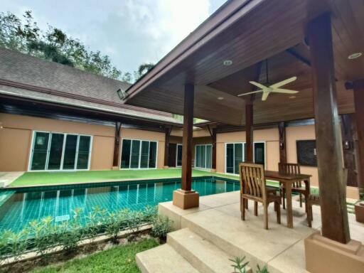 Covered patio area with table and chairs near swimming pool