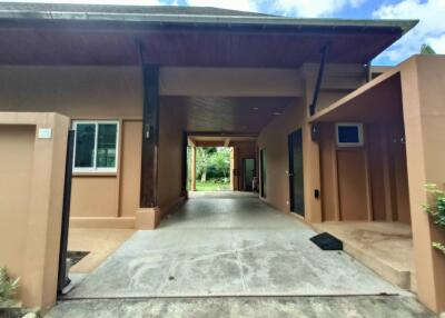 Modern detached building entrance with driveway, large windows, and covered area