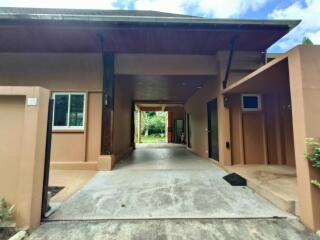 Modern detached building entrance with driveway, large windows, and covered area