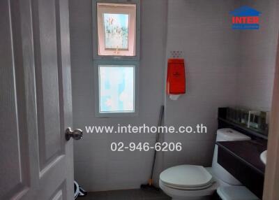 Bathroom with toilet and sink, featuring a window and storage space