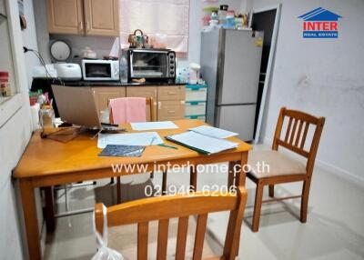 Small kitchen area with wooden table and chairs, refrigerator, microwave, and cabinets