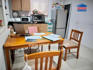 Small kitchen area with wooden table and chairs, refrigerator, microwave, and cabinets