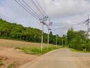 View of a rural road with utility poles and green hills