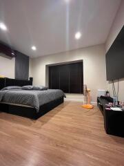Modern bedroom with large bed, wooden floor, and wall-mounted TV
