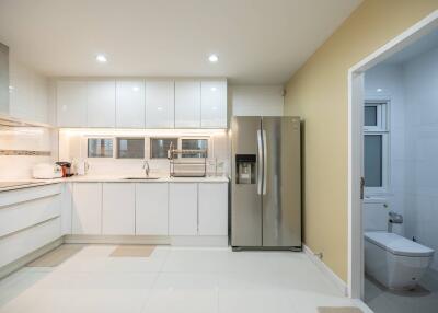 Modern kitchen with white cabinets, stainless steel refrigerator, and adjacent bathroom