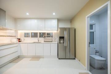 Modern kitchen with white cabinets, stainless steel refrigerator, and adjacent bathroom