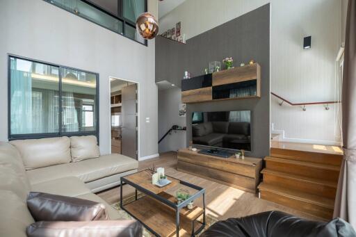 Modern living room with a high ceiling, hardwood floors, and contemporary furnishings