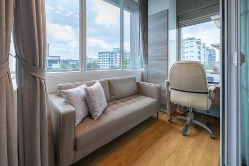 Bright study room with a sofa, office chair, and large windows