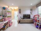 Bright living room with TV, shelving units, children's play area, and modern furnishings