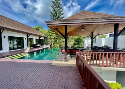 Spacious outdoor area with a wooden deck, swimming pool, and covered patio
