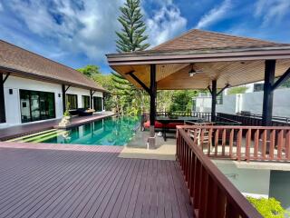 Spacious outdoor area with a wooden deck, swimming pool, and covered patio