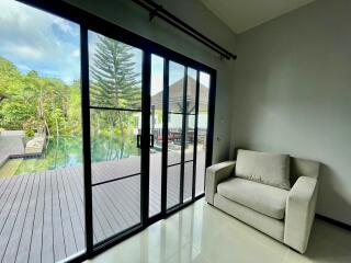 Living room with a view of outdoor pool area through sliding glass doors
