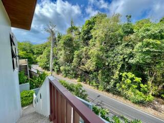 balcony with railing overlooking a road and dense greenery