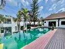 Spacious outdoor area featuring a modern swimming pool surrounded by trees and contemporary buildings