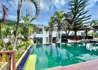 Luxurious outdoor pool surrounded by tropical plants and modern villas