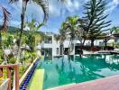 Luxurious outdoor pool surrounded by tropical plants and modern villas