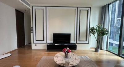 Modern living room with a TV, coffee table, and large window