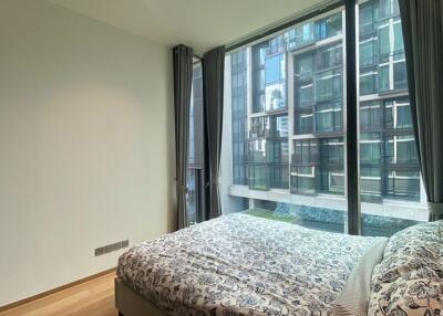 A bedroom with a large window and a view of a neighboring building