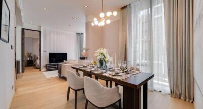 Modern living and dining area with a set dining table, a cozy living space, a TV, and large windows with curtains