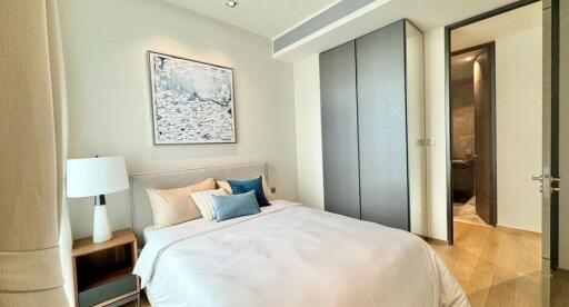Modern bedroom with lamp, artwork, wardrobe, and comfortable bedding