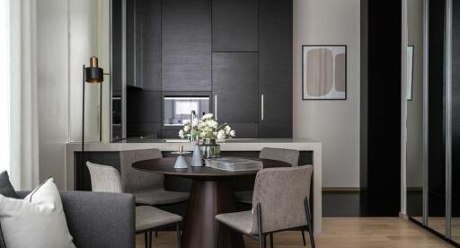 Modern kitchen and dining area with dark cabinets, a round dining table, and contemporary decor.