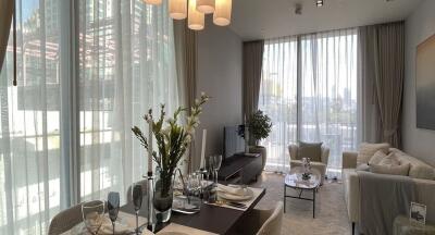 Modern living room with large windows, a dining area, and neutral decor