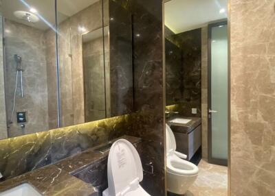 Modern bathroom with brown marble walls, glass shower, and toilet