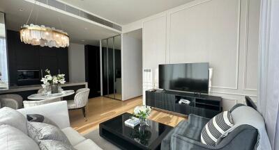 Modern living room with a flat-screen TV, coffee table, and seating area next to a dining space