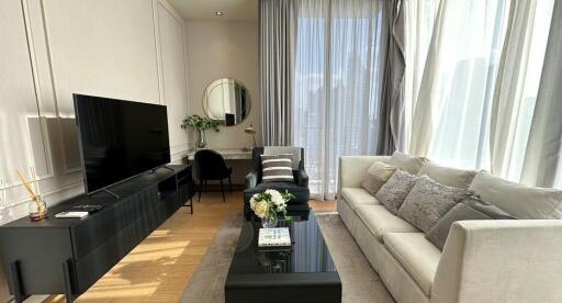 Modern living room with a large TV, sofa, coffee table, and natural light