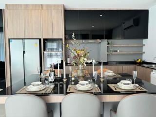 Modern kitchen with dining area, wooden cabinets, and black countertops