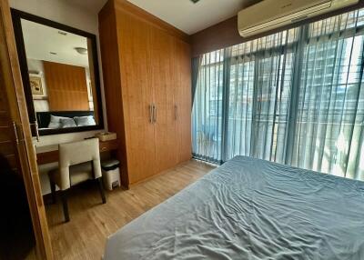 well-lit bedroom with a large window, wooden wardrobe, and a study area