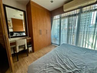 well-lit bedroom with a large window, wooden wardrobe, and a study area