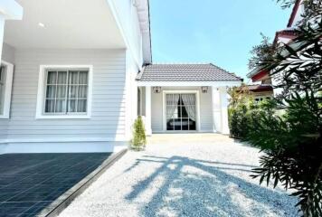 Exterior view of a modern light-colored single-story home with a tile roof and a front patio