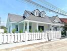 Exterior view of a modern house with gable roof and white picket fence