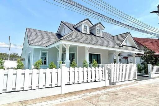 Exterior view of a modern house with gable roof and white picket fence