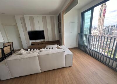 Living room with a view of the city, featuring a modern couch, flat-screen TV, and wooden flooring