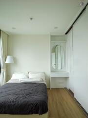 Modern bedroom with bed, bedside lamp, and a built-in wardrobe