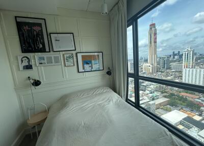 A bedroom with a city view through large windows
