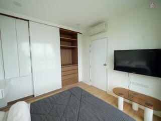 Bedroom with bed, sliding door closet, air conditioner, TV, and small table