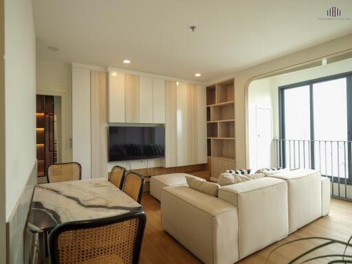 A modern living room with a beige sofa, TV, and dining area