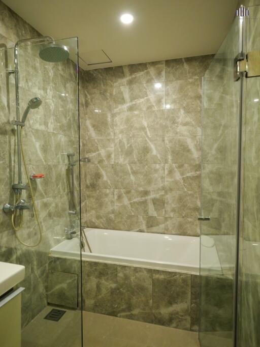 Modern bathroom with marble tiles, shower, and bathtub