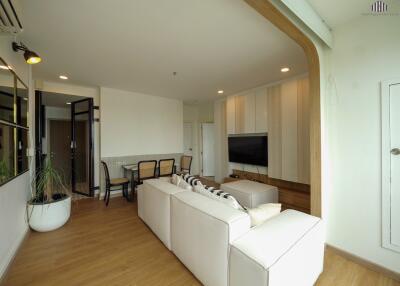 Modern living room with white sofa, TV, and dining area