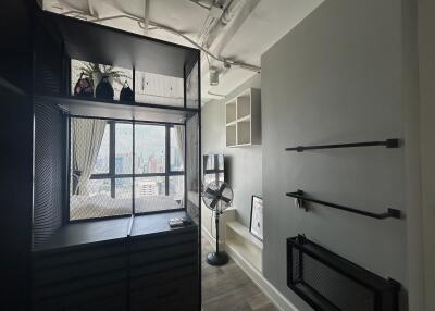 Modern, industrial-style bedroom with large window, shelving, and fan