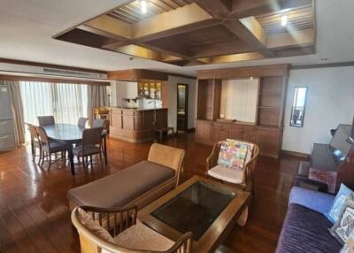 Spacious and well-lit living room with wooden furniture and flooring, dining area, and open kitchen