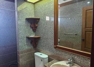 Bathroom with a toilet, sink, large mirror, and wall-mounted shelves