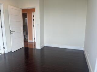 Minimalist bedroom with dark wooden floor and open door