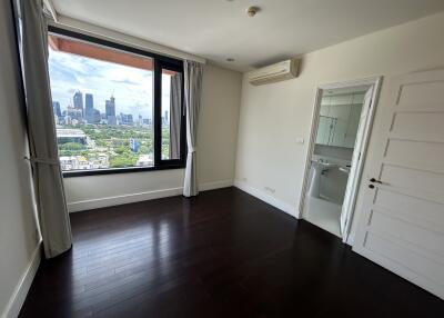 A bedroom with a window view of the city and an adjacent bathroom