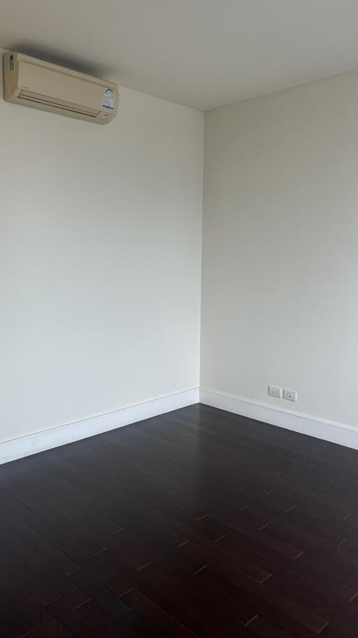 Empty living room with dark wooden floor and wall-mounted air conditioner