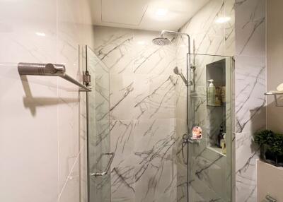 Modern bathroom with glass shower door and marble tiles